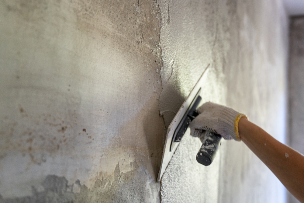 Imagen de un obrero alisando la pintura de una pared. La imagen se puede ver en la página Filosofía y servicios.